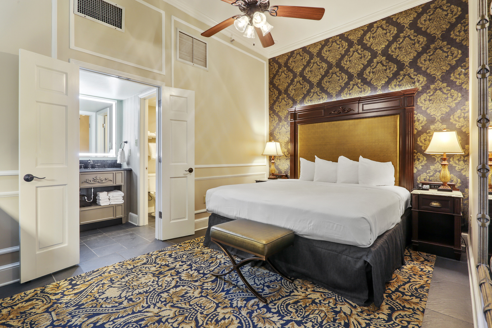A hotel room with a large bed, ceiling fan, and nightstands.